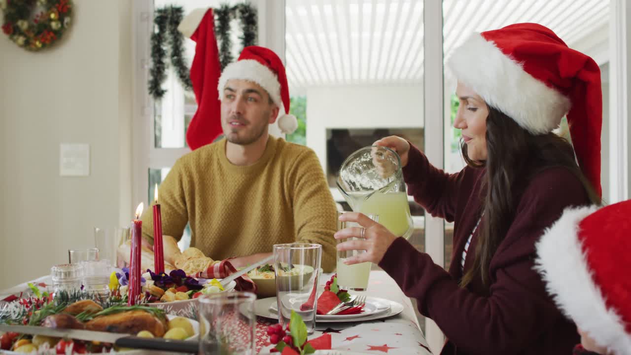 행복한 백인 다세대 가족이 산타 모자를 입고 크리스마스 식사를 하고 있습니다.