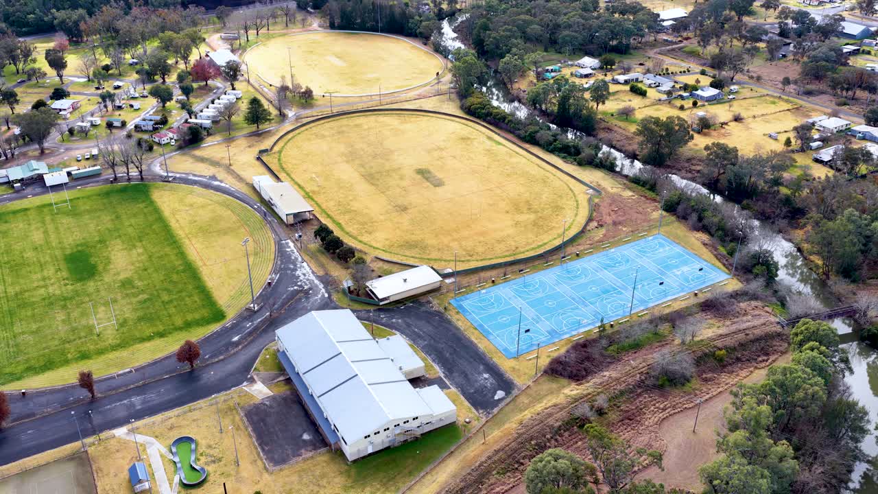 Aerial footage captures sports fields, tennis courts, and buildings in Coonabarabran, New South Wales, under natural daylight with smooth, steady camera movement