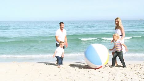 family playing with a ball on the sand