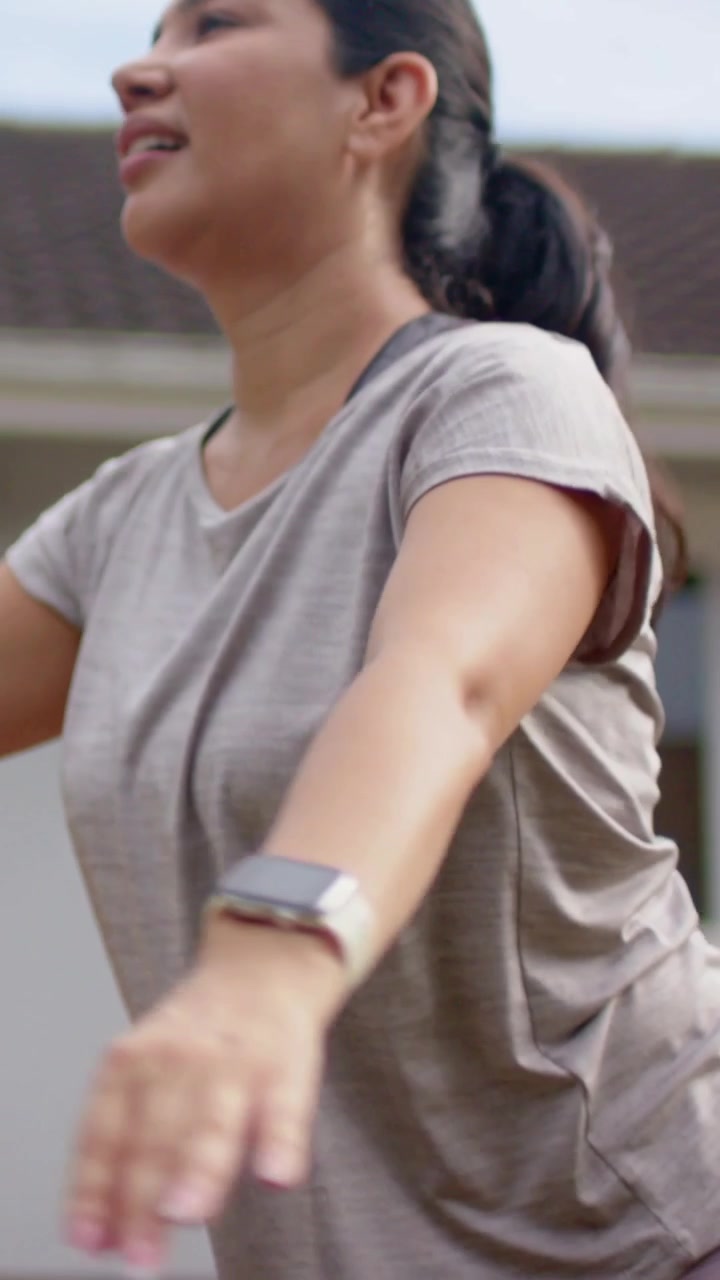 Video verticale: Inizio, donna con smartwatch e leggings che si allunga in avanti per il riscaldamento vicino a casa.