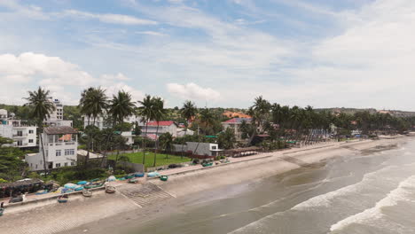 Vuelo-Aéreo-Sobre-La-Playa-De-Arena-De-Palmeras-Tropicales-En-Mui-Ne,-Un-Pueblo-Pesquero-Costero-En-El-Centro-Sur-De-La-Provincia-De-Bình-Thuan-En-Vietnam