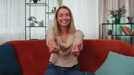 mujer joven feliz mirando con aprobación a la cámara mostrando los pulgares hacia arriba, como un signo positivo, buenas noticias