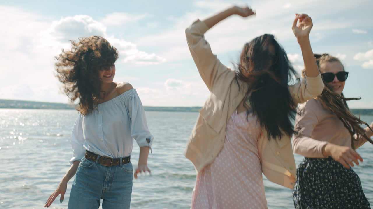 Three friends dancing on the beach by the lake