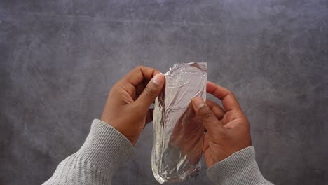 close-up of hands unwrapping a chocolate bar