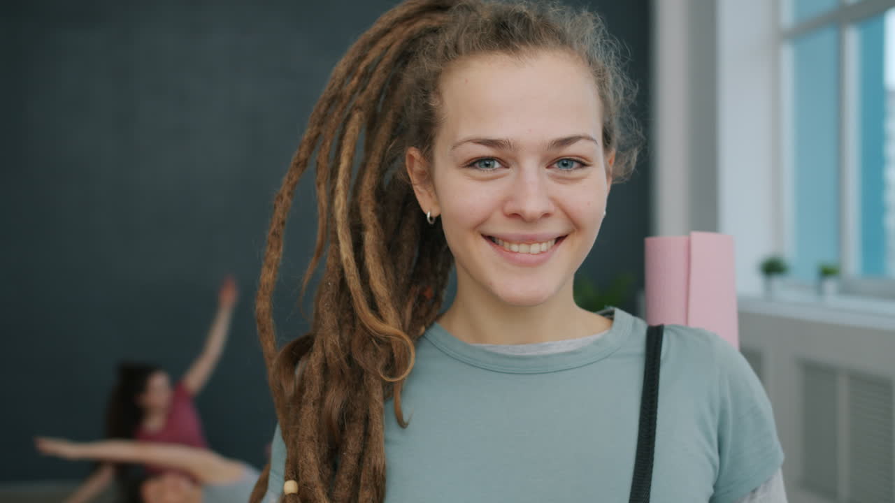Smiling Woman with Dreadlocks Holding Yoga Mat