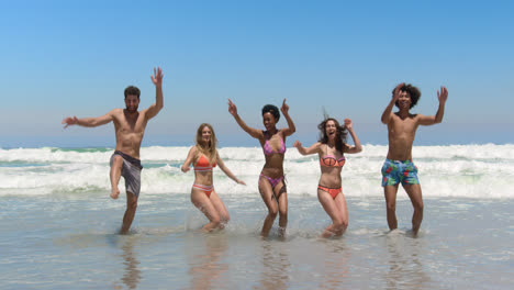 Young-friends-jumping-together-at-beach-4k