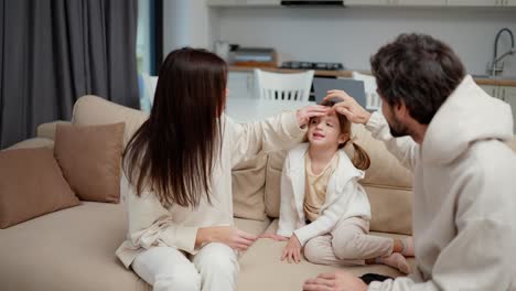Family-of-three-are-at-the-living-room-together,-father-caress-his-small-daughter