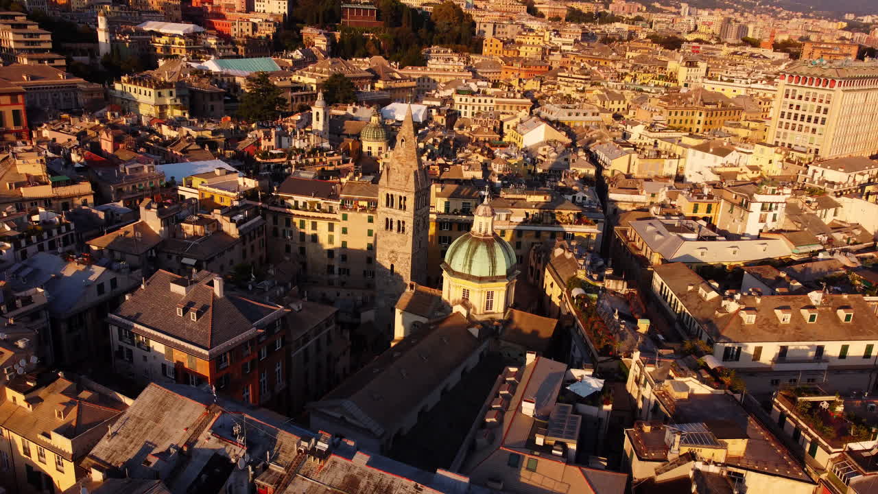 Drone moving forward with tilt down over Genoa’s historical center, focusing on San Lorenzo Cathedral at sunset