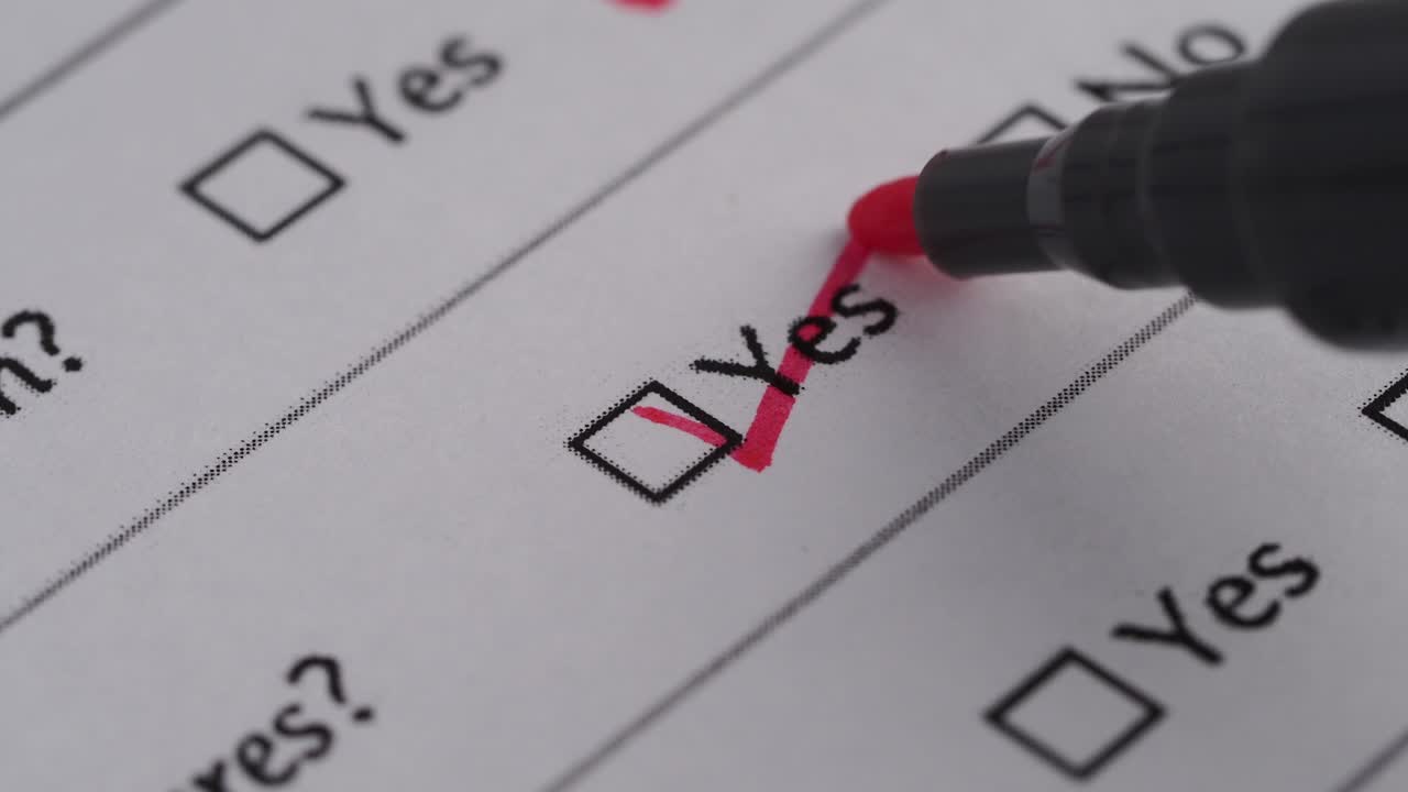 Person Marking 'Yes' Checkbox on a Paper Form with Red Marker