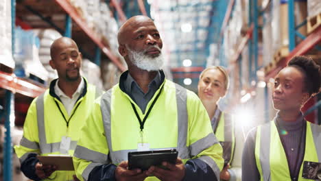 a team of warehouse workers checking inventory and communicating on tablets