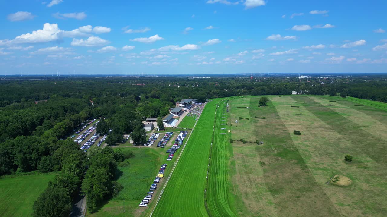 Jockeys on racehorses on horse racing track, showcasing the vibrant green turf, stands filled with spectator landscape beyond. Nice aerial view flight panorama orbit drone