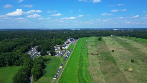 jockeys on racehorses on horse racing track, showcasing the vibrant green turf, stands filled with spectator landscape beyond. nice aerial view flight panorama orbit drone