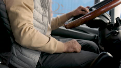 the camera focuses on the hands of an older worker on stick shift and steering wheel of a truck