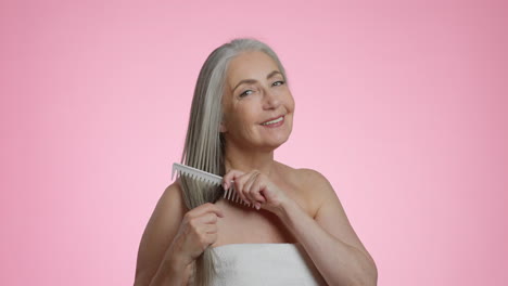 smiling senior woman combing her long gray hair