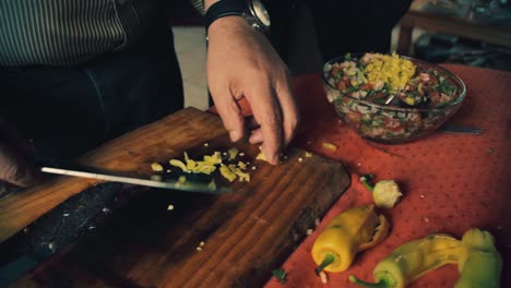 cerca de las manos del chef agregando pimiento verde a la ensalada.