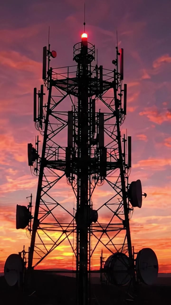 Torre de comunicaciones en silueta contra un vibrante cielo al atardecer: Una vista impresionante de la tecnología moderna fusionándose con la belleza de la naturaleza