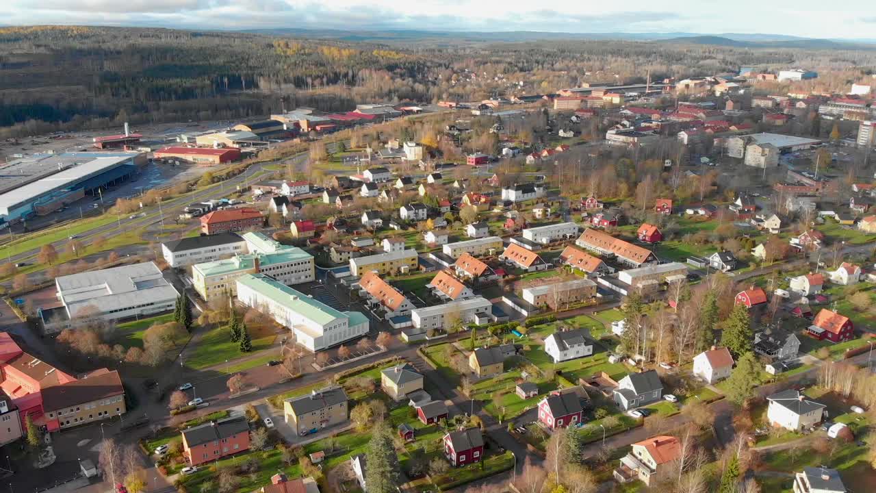 Drone footage panning over a residential area and a school in a small town with some industries in the background