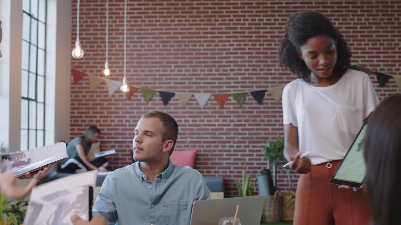 jóvenes empresarios se reúnen líder de equipo mujer presentando datos financieros utilizando una tableta mostrando colegas multiétnicos ideas de marketing en la presentación de la sala de juntas de la oficina