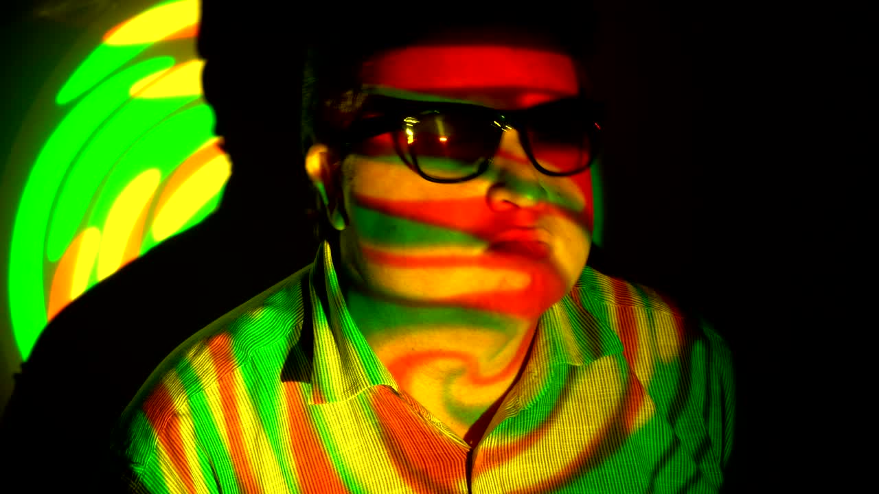 retrato de un hombre gordo en un haz de luz multicolor.