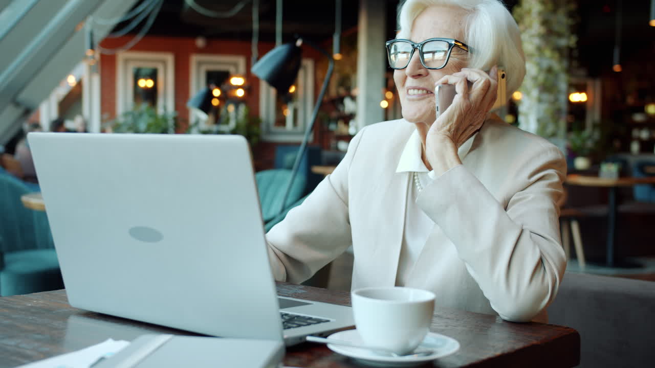 Donna anziana che lavora al portatile in un caffè