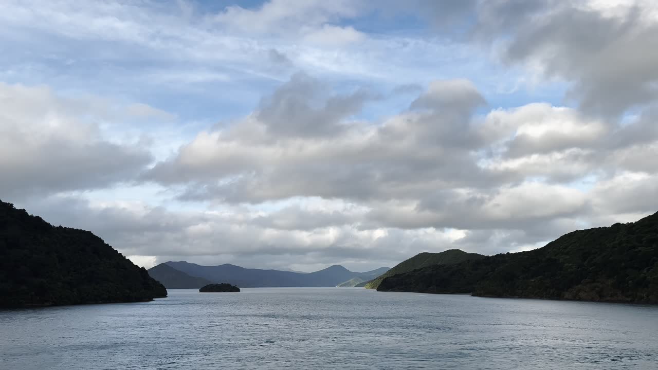 Peaceful bay area in New Zealand under a cloudy sky, concept of serene nature, calm waters, scenic coastline, untouched wilderness, and remote island tranquility.