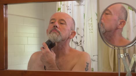 caucasian male using electrical trimmer to cut his hair and beard