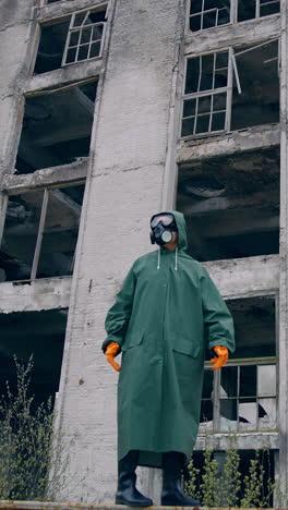 lab technician in a mask and chemical protective suit walking on dry ground and looking around while thinking about pollution. ecological catastrophe concept. vertical video