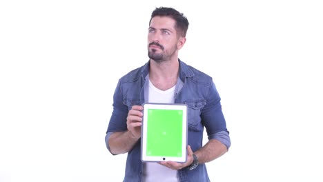 fotografía de estudio de un hombre guapo pensando y sonriendo mientras sostiene una tableta digital con tecla de croma copia espacio contra fondo blanco