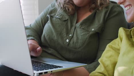 Pareja-De-Lesbianas-Caucásicas-Usando-Una-Computadora-Portátil-Y-Sentada-En-El-Sofá