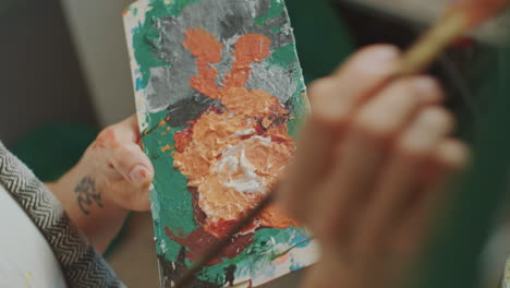 close-up of artist holding palette while painting on canvas