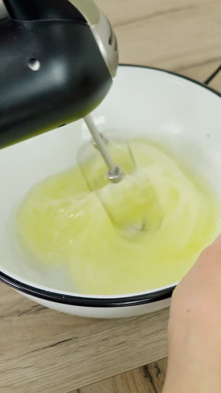 Close-up vertical shot of a mixer whipping egg whites, a key step in making tiramisu.
