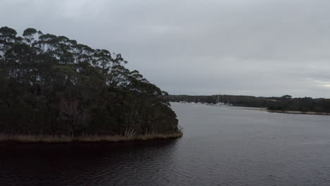 Antenne:-Drohnenverfolgung-Um-Bäume-Herum,-Um-Boote-Zu-Enthüllen,-Die-Auf-Einem-See-In-Der-Nähe-Von-Strahan,-Tasmanien,-Australien,-Schwimmen