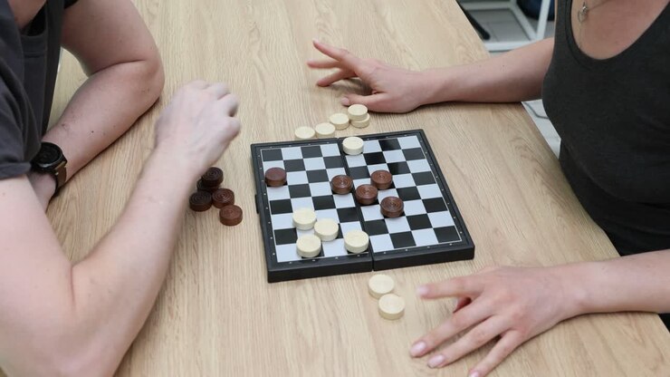 People playing checkers on a wooden table