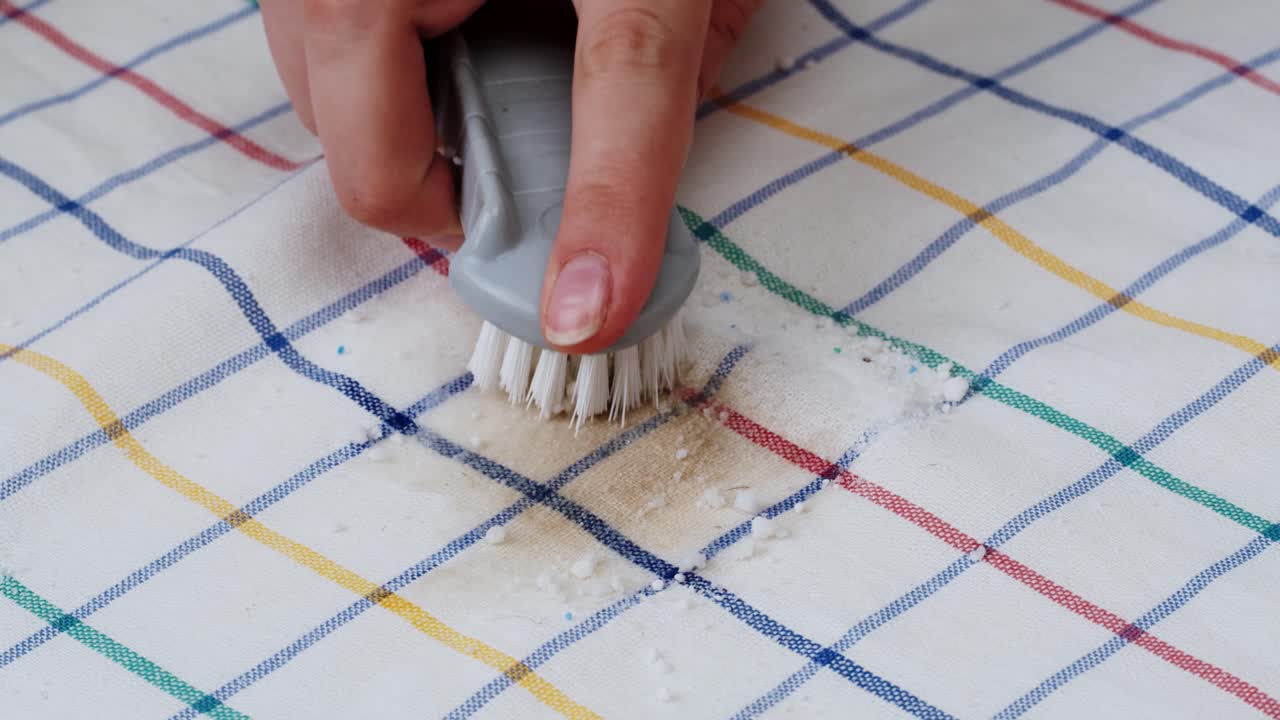 Close-Up of Hand Brushing a Stain on Checkered Fabric