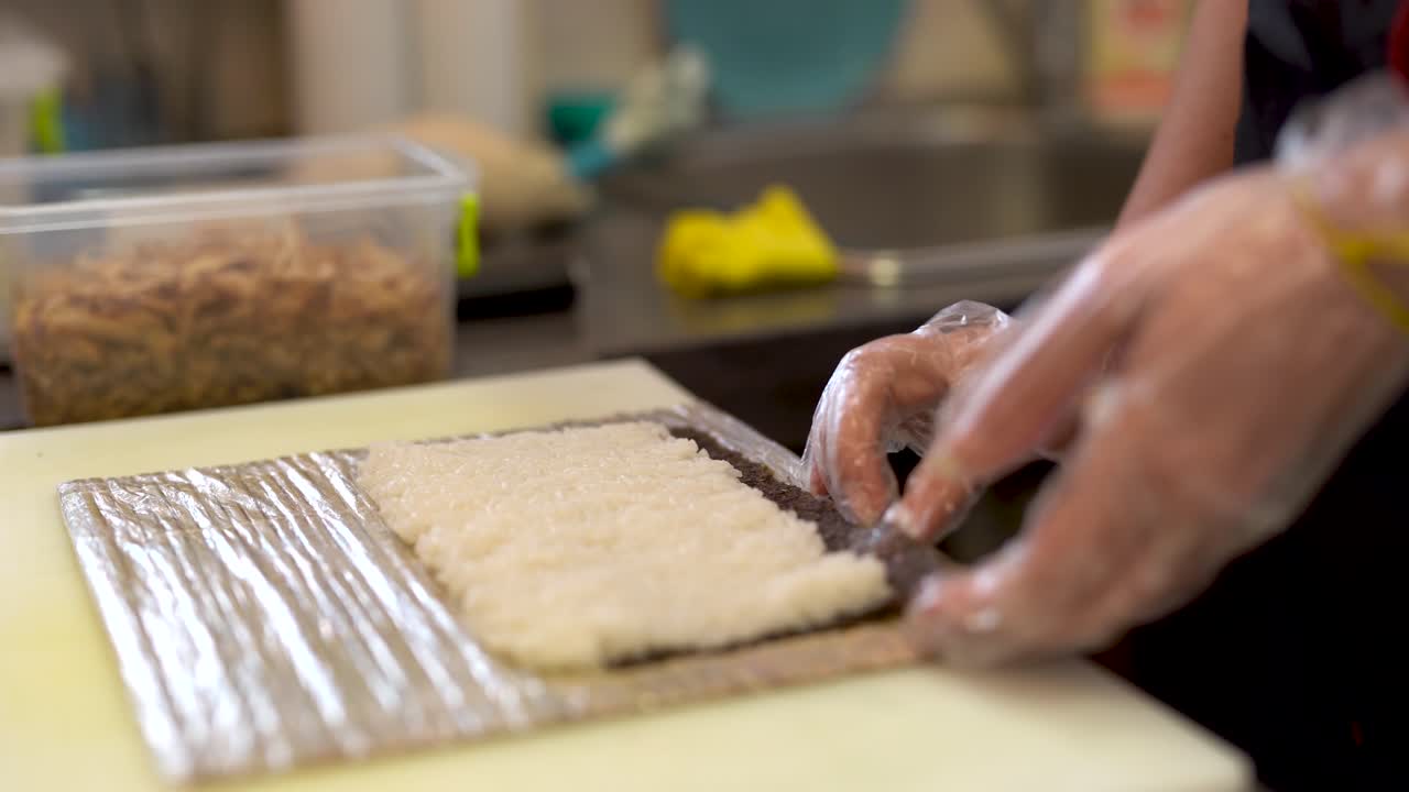 The cook finishes sticking and gluing together the sushi rice and the nori