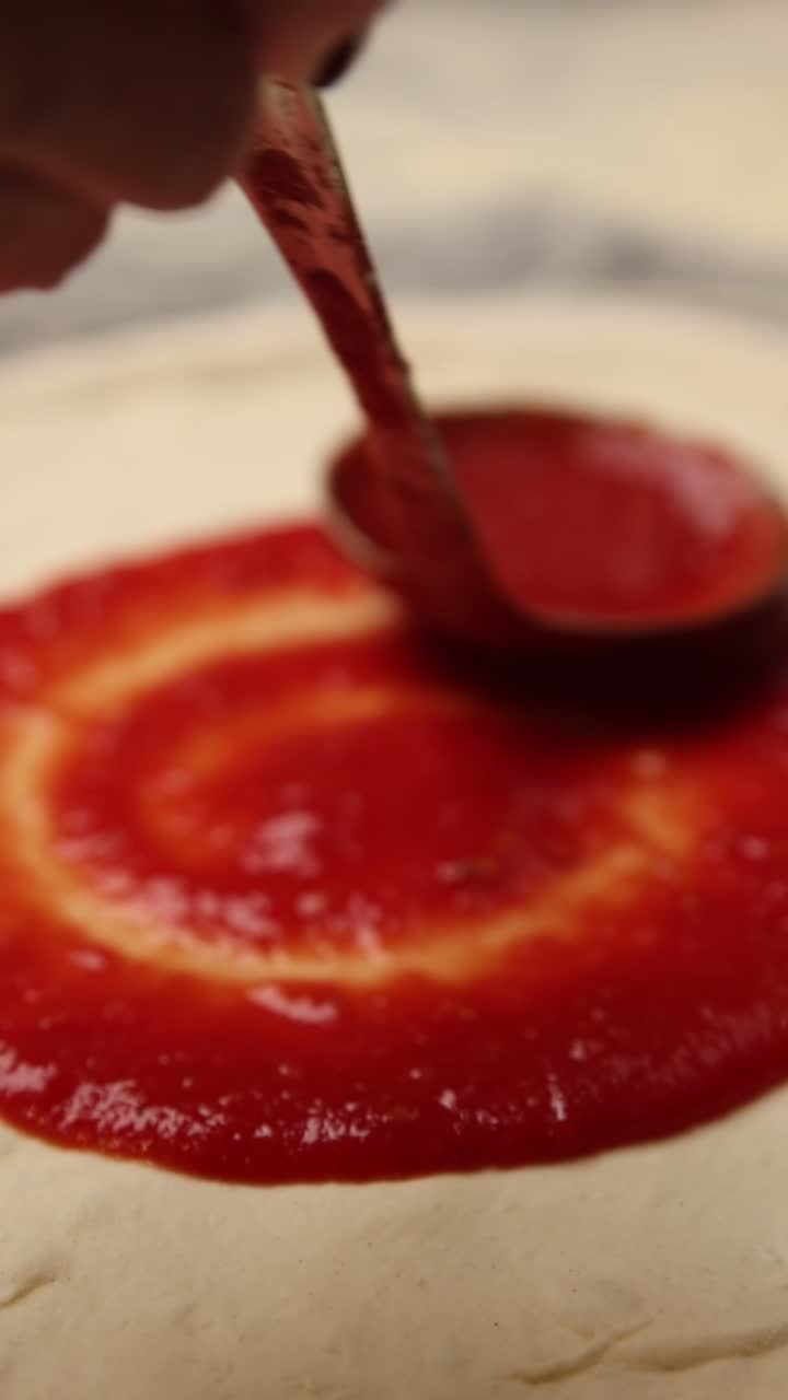 Spalmare salsa di pomodoro fresca sull'impasto della pizza
