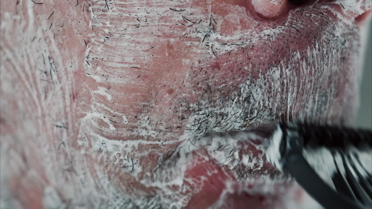 Close up of a man shaving his beard with a razor