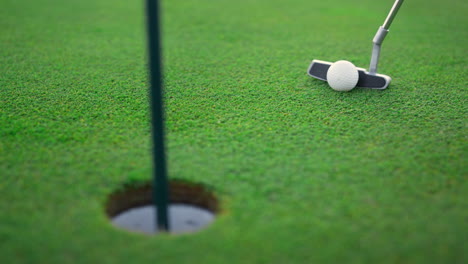 una pelota de golf profesional en un agujero de golf. un club de golf en el campo verde.