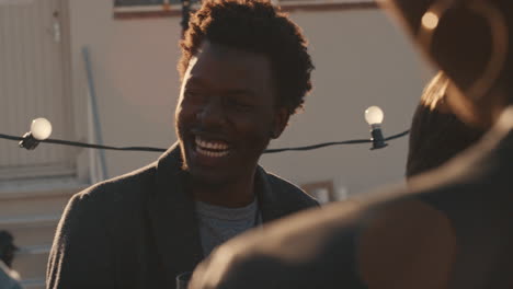 group of diverse friends hanging out together enjoying rooftop party at sunset happy african american man socializing drinking alcohol having fun on weekend celebration