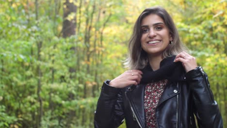 Brunette-girl-in-the-forest-looks-happy,-brushing-her-hair-and-smiling-at-the-camera