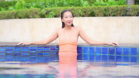 beautiful exotic woman in swimsuit enjoying in swimming pool on her luxury tropical vacation, full frame