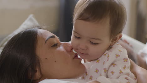 mujer feliz abrazando a su hija mientras está acostada en la cama por la mañana