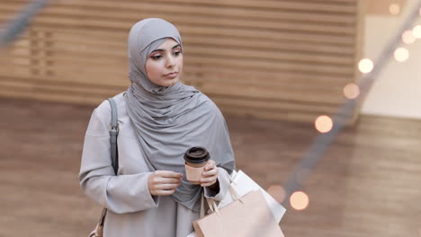muslim woman shopping in a mall with coffee
