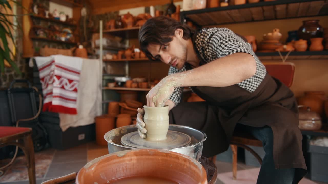 el ceramista utiliza la rueda del alfarero y crea un producto de arcilla hecho a mano