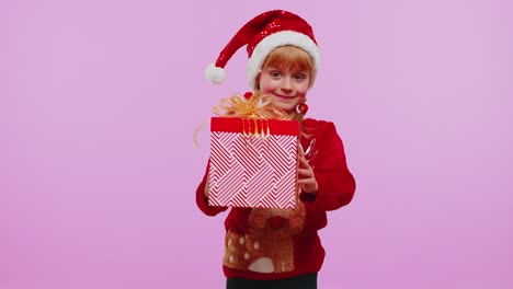 Una-Niña-Pequeña-Adolescente-Graciosa-Viste-Un-Suéter-Rojo-De-Navidad-Presentando-Una-Caja-De-Regalo-De-Navidad,-Venta-De-Compras