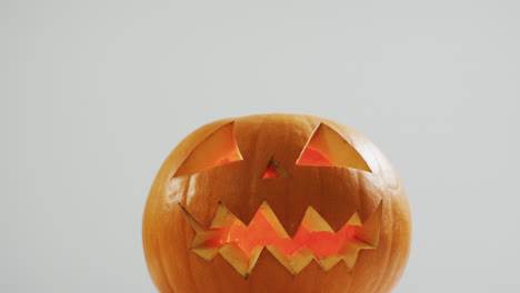 Close-up-view-of-scary-face-carved-halloween-pumpkin-against-grey-background