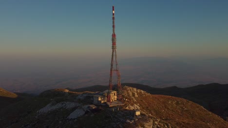 aerial of tall telecommunications tower on a mountain peak at sunrise