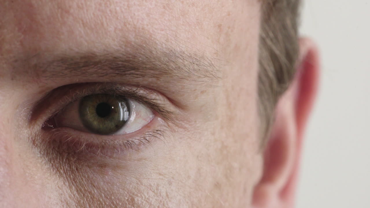 cerca de un joven hombre caucásico ojo buscando feliz aislado en fondo blanco