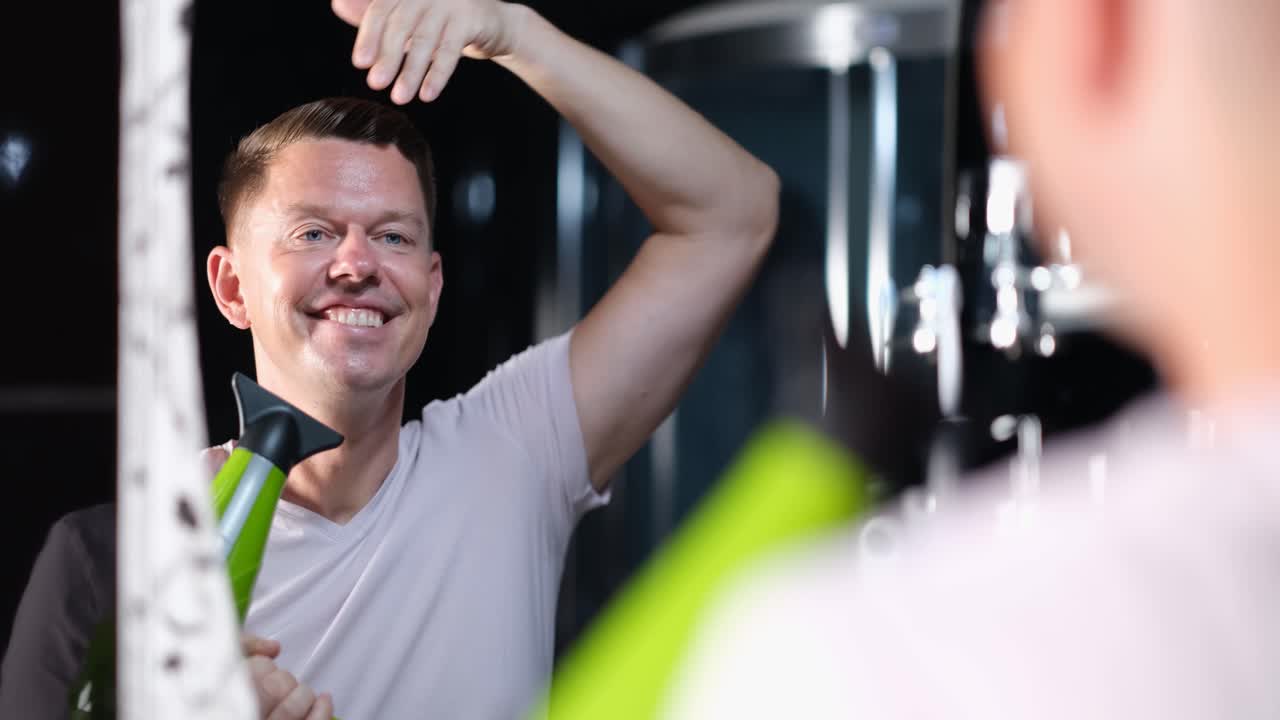 Man styling hair with hair dryer in mirror