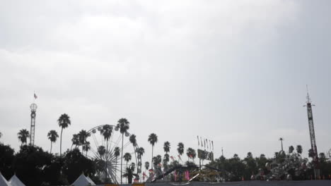 fair rides before opening, ferris wheel, palm trees, cloudy gloomy sky